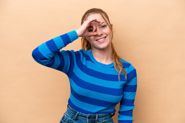 Wall Mural - Young caucasian woman isolated on beige background showing ok sign with fingers