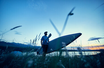 Wall Mural - Man with paddle and SUP board near lake at sunset