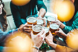 Fototapeta Londyn - Group of happy friends drinking and toasting beer glasses at brewery pub restaurant - Young people enjoying happy hour sitting at bar table - Food, beverage and life style concept