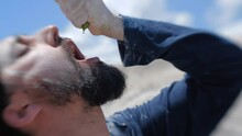 Close Up Exhausted Traveler In Dirty Clothes Trying To Squeeze A Drop Of Water Out Of A Desert Cactus. Survival Training And Instructor Concept Lens Baby Shot. 200 Fps Slow Motion