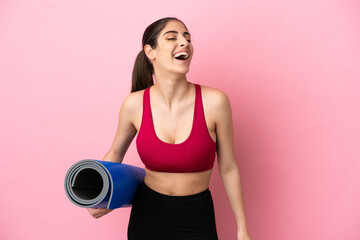 Wall Mural - Young sport caucasian woman going to yoga classes while holding a mat laughing