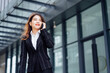 © Vilaysack - Business woman talking on mobile phone and smiling, Happy business woman, business woman with mobile phone in hand looking at camera, Image of pretty smiling woman in fashion