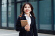 © Vilaysack - Portrait of young Asian business woman using digital tablet, professional manager holding digital tablet computer using software applications standing in front of modern business building