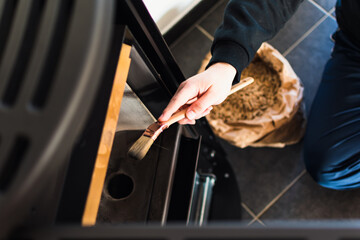 Man cleaning pellet stove with brush