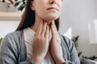 Selective focus of unhealthy sad young caucasian woman hold hands over sore throat feeling discomfort. Painful neck and frowning, thyroid disorders, suffering sore throat, tonsils inflammation concept