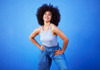 © Emily/peopleimages.com - Fashion, natural hair and black woman isolated on a blue background for gen z, youth or cool portrait with mockup. Afro person or beautiful model with style, confidence and happy in studio space