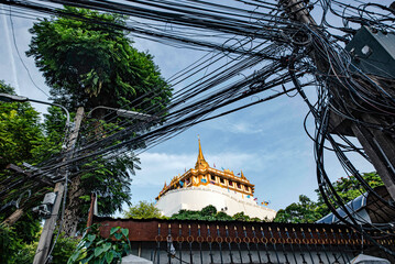 Wall Mural - Phra That Phukhao Thong viewed through tangled wires perched on a hill in Wat Saket, Bangkok, Thailand.