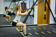 © BullRun - Young sporty female exercising with TRX straps