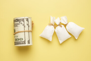 A picture of roll fake money with 3 flour bag on yellow background. Food trading and supply concept.