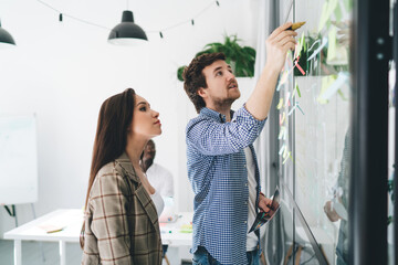 Sticker - Happy young coworkers standing near glass wall and working on project in office