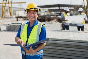 Wall Mural - Portrait Asia senior engineer man holding document file with team working with paper work and precast cement factory background