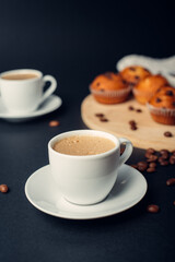 Dos tazas de café, desayuno con muffins de chocolate, en una bandeja de madera, granos de café en fondo azul oscuro