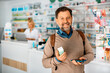 © Drazen - Happy man shopping in drugstore and looking at camera.