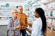 © Drazen - Senior couple talks to black female pharmacist in drugstore.