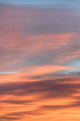 Wall Mural - Sky with soft and fluffy pastel orange pink and blue colored clouds. Sunset background. Nature. sunrise. Instagram toned style. Vertical