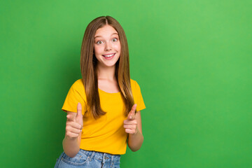 Poster - Portrait of cheerful positive girl toothy smile point fingers camera you empty space ad isolated on green color background