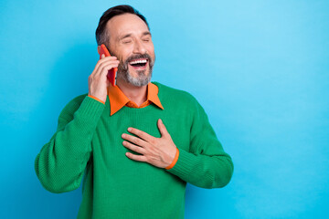 Sticker - Photo portrait of mature handsome man hand touch chest talking phone laugh wear trendy green garment isolated on blue color background