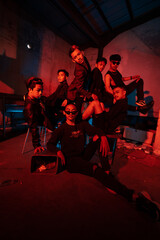 a group of Asian teenagers in black clothes posing very naughty with their friends in a warehouse with a red light