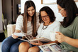 © kleberpicui - Three generation family looking at old photo album in living room.
