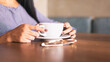 © Cavan Images - close-up of hands on a coffee cup on the table, hipster concept