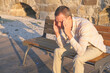 © Tatonka - Man has a headache and he sits on a bench in the big city