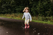 © Cavan Images - Young girl splashes in puddle on walking trail on a cloudy fall day