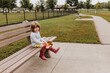 © Cavan Images - Young girl sits on bench at dog park holding autumn leaves