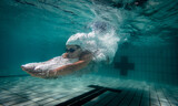 Fototapeta Łazienka - Underwater photo of a female swimmer diving into an olympic standard swimming pool