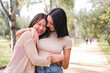 © Raul Mellado - couple of happy women embracing and smiling during a date in a park, concept of friendship and love between people of the same sex