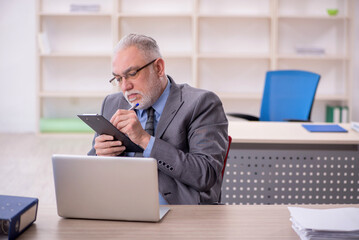 Old male employee working in the office