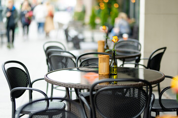 Outdoor restaurant table beautifully decorated with rose flower in a bottle in Vilnius, Lithuania, on nice summer day.