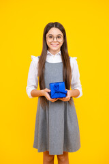 Canvas Print - Teenager child girl holding present box isolated over yellow studio background. Present, greeting and gifting concept. Birthday holiday concept.