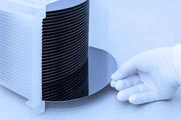 Poster - Silicon wafer inspection. A batch of silicon wafers packed in a plastic storage box in the clean room of a semiconductor foundry ready for microchip production. Banner.