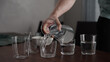 Man pour water into glasses from carafe on walnut table