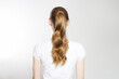 Closeup curly wavy imperfect pony tail back view isolated on white background. Quick easy Not ideal realistic Hair-styles for long hair. A young woman blond tied ponytail. Lazy home made hairstyles.