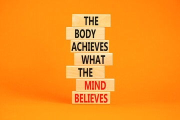 Mind and body symbol. Concept words The body achieves what the mind believes on wooden blocks. Beautiful orange table orange background. Copy space. Motivational mind and body concept.