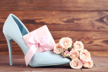 Canvas Print - Flowers of roses, gift box and blue high-heeled shoe on brown wooden background