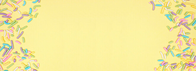 Aufkleber - Colorful candy sprinkles double border. Above view on a yellow banner background. Pastel Easter color theme. Copy space.