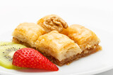 Fototapeta Na ścianę - Multi-layered walnut baklava decorated with kiwi, strawberries and walnuts on a white plate