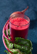 Fresh homemade organic red beet juice on a dark blue surface with copy space