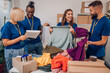© Zamrznuti tonovi - Diverse volunteers working in a charity donation center and packing clothes and food