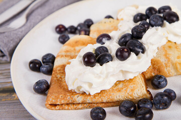 Wall Mural - Crepes with blueberry fruit and whipped cream on a wooden background