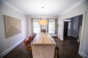 Wall Mural - A modern dining room with a stained with a stained wood table, bench seating and upholstered chairs with a hanging drum light fixture