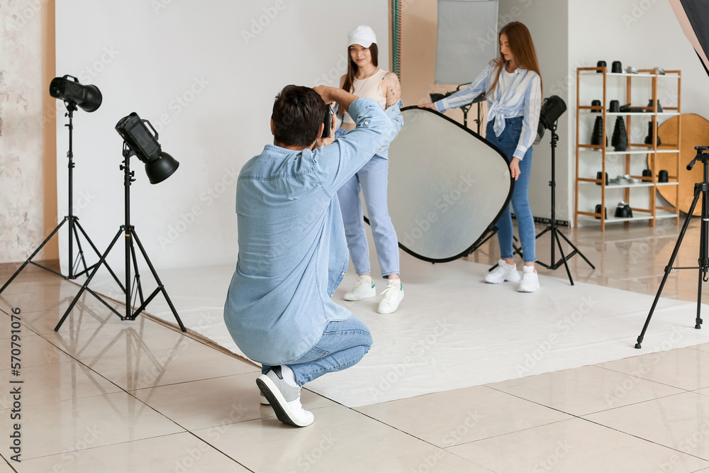 Male photographer and his assistant working with beautiful model in studio