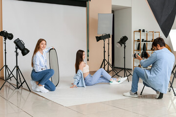 Poster - Male photographer and his assistant working with beautiful model in studio