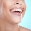 © Anela R/peopleimages.com - Teeth, dental and woman with face and smile, beauty and oral healthcare, clean mouth with fresh breath in studio. Veneers, orthodontics and lips with skin, glow and cosmetic care on blue background