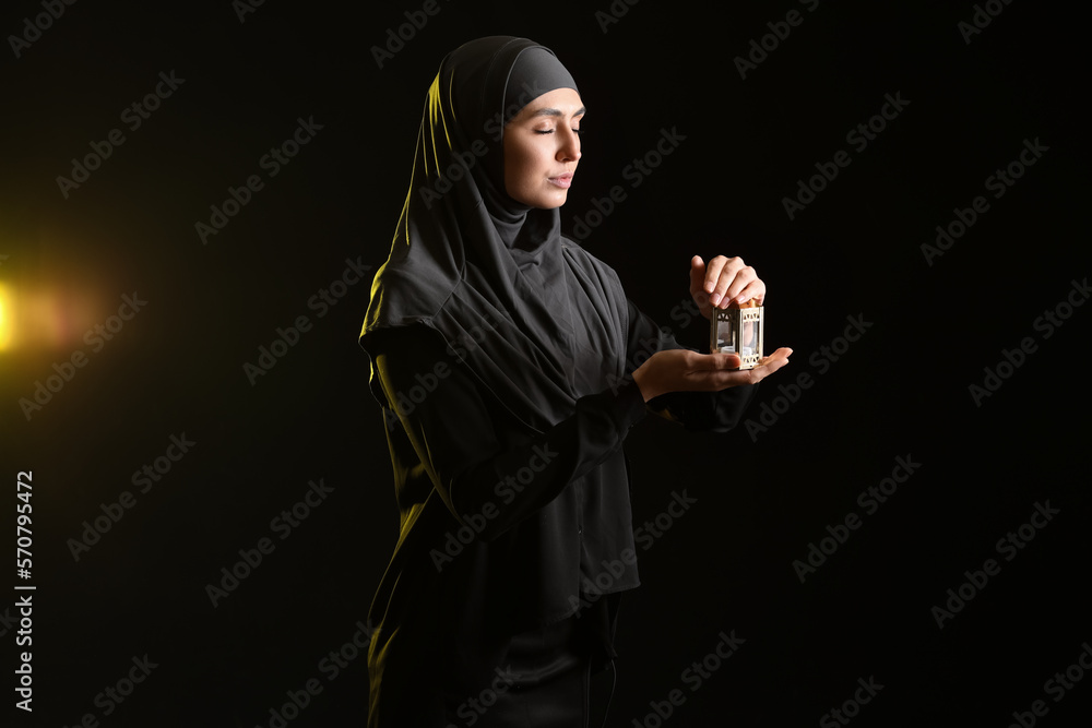 Praying Muslim woman with lantern on dark background