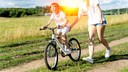 mom teaches son to ride a bike in the park