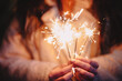 © Cavan Images - Female hands holding sparklers during Christmas in city