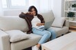 © SHOTPRIME STUDIO - Woman freelancer on her day off sitting on the couch with a laptop at home and watching series and tv shows, smile